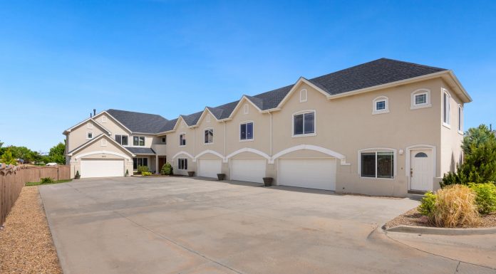 A modern suburban residential building featuring a large driveway under a clear blue sky.