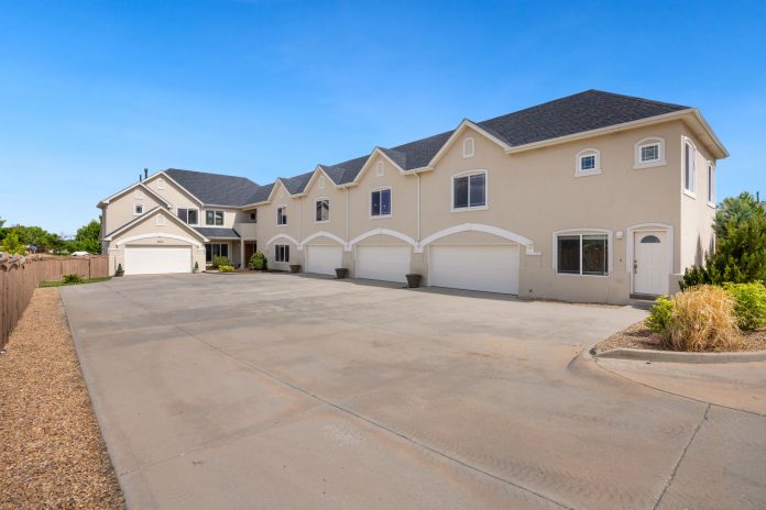A modern suburban residential building featuring a large driveway under a clear blue sky.