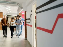 A diverse group of teenagers walking together in a modern school hallway.