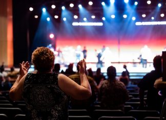 A lively concert setting with an engaged audience clapping, under vibrant stage lights.