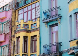 Vibrant city scene with colorful apartment facades of pink, yellow, and blue.