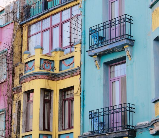 Two Jersey City Councilmen Push for Greater Tenant Protections in Tax-Abated Buildings Vibrant city scene with colorful apartment facades of pink, yellow, and blue.