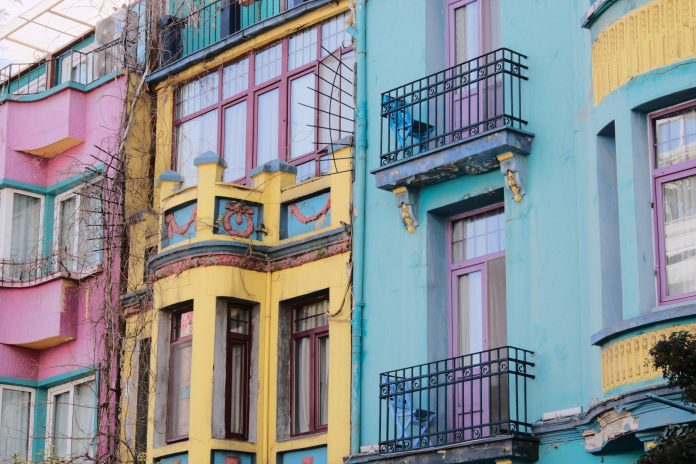 Vibrant city scene with colorful apartment facades of pink, yellow, and blue.