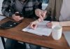 A couple analyzing financial documents and using a calculator at a home table.