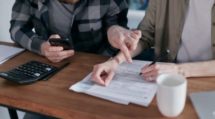 A couple analyzing financial documents and using a calculator at a home table.