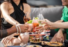 Group of friends clinking glasses with cocktails at an outdoor terrace party in Dubai.