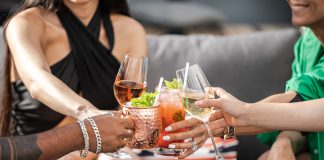 Group of friends clinking glasses with cocktails at an outdoor terrace party in Dubai.