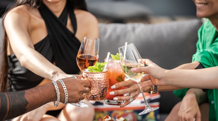 Group of friends clinking glasses with cocktails at an outdoor terrace party in Dubai.