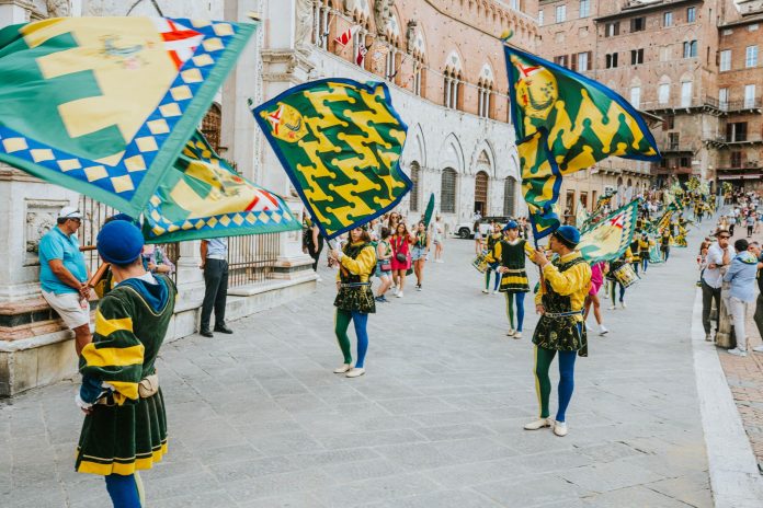 your-guide-to-the-best-local-events-this-weekend Vibrant street parade with flags and performers in historic square, capturing the lively festival atmosphere.