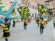 Vibrant street parade with flags and performers in historic square, capturing the lively festival atmosphere.