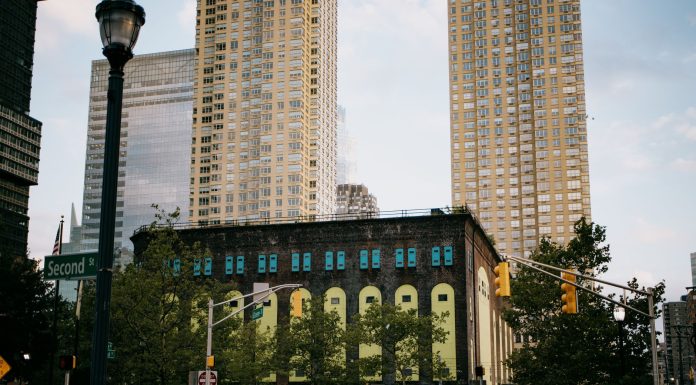 A vibrant intersection in Jersey City with towering skyscrapers and a historic building.
