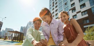Diverse group of children laughing and playing outdoors in a city playground.