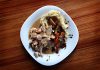 Best Dominican Restaurants in North Bergen, NJ (2026 Guide) A savory dish of meat and vegetables with mashed potatoes on a wooden table.