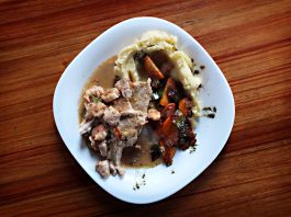 A savory dish of meat and vegetables with mashed potatoes on a wooden table.