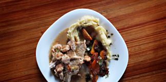 A savory dish of meat and vegetables with mashed potatoes on a wooden table.