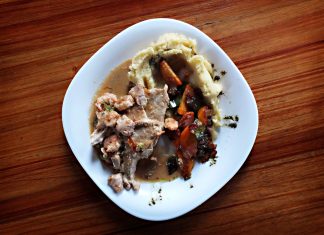 A savory dish of meat and vegetables with mashed potatoes on a wooden table.