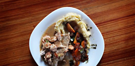 A savory dish of meat and vegetables with mashed potatoes on a wooden table.