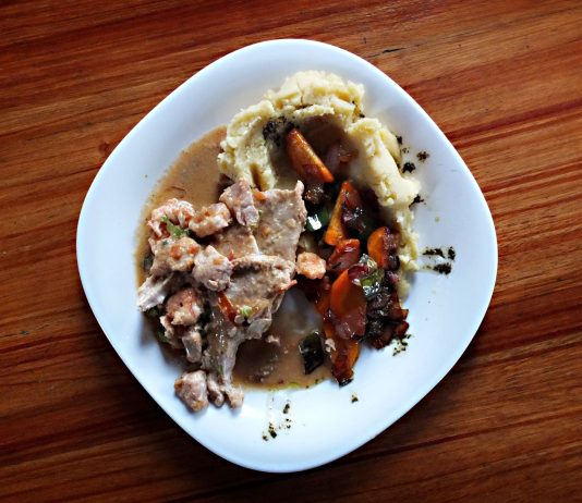 A savory dish of meat and vegetables with mashed potatoes on a wooden table.