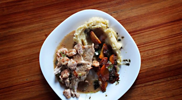 A savory dish of meat and vegetables with mashed potatoes on a wooden table.