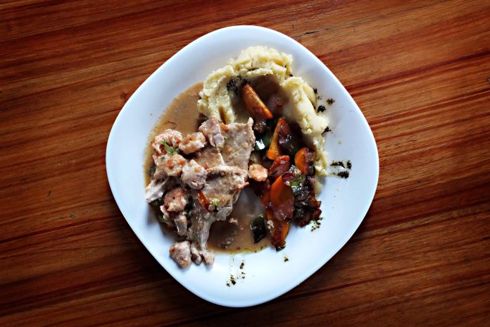 best-dominican-restaurants-north-bergen A savory dish of meat and vegetables with mashed potatoes on a wooden table.