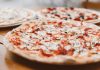 Close-up of freshly baked pizzas with mushrooms served on a wooden table.