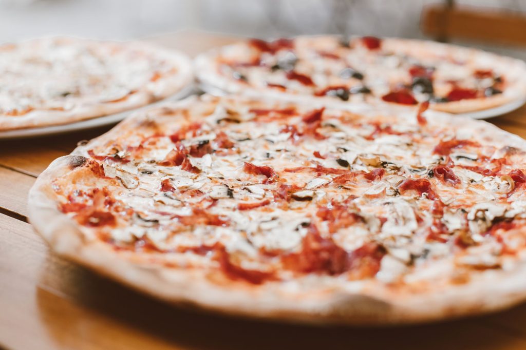 Close-up of freshly baked pizzas with mushrooms served on a wooden table.