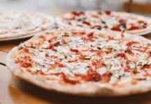 Close-up of freshly baked pizzas with mushrooms served on a wooden table.