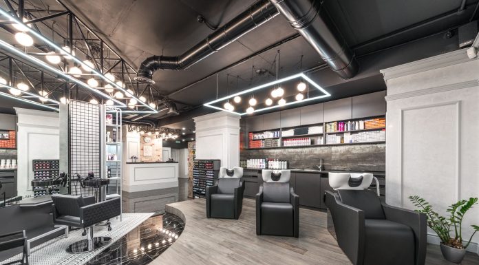 Comfortable backwash chairs with sinks near potted plant placed in contemporary beauty salon with bright illumination and abundance of cosmetology products