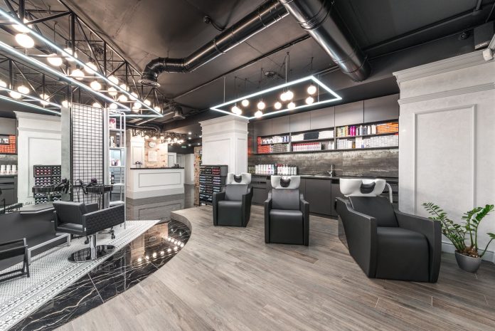 best-salons-barbershops-bayonne-2026 Comfortable backwash chairs with sinks near potted plant placed in contemporary beauty salon with bright illumination and abundance of cosmetology products