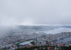 Aerial view of Bergen, Norway, with its harbor and surrounding hills on a cloudy day.