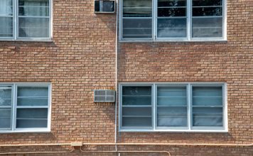Close-up of a brick apartment facade featuring multiple modern aluminum windows.