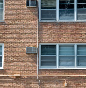 Close-up of a brick apartment facade featuring multiple modern aluminum windows.