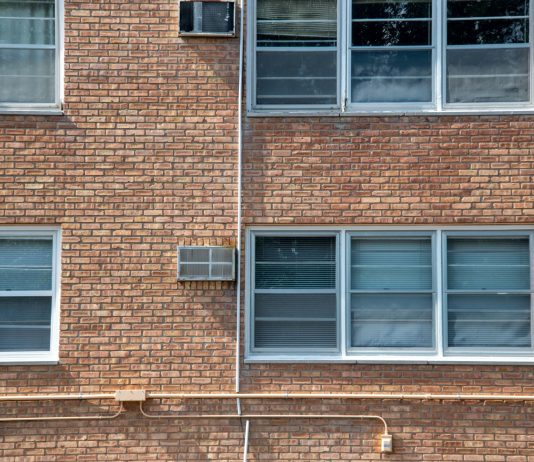 Close-up of a brick apartment facade featuring multiple modern aluminum windows.