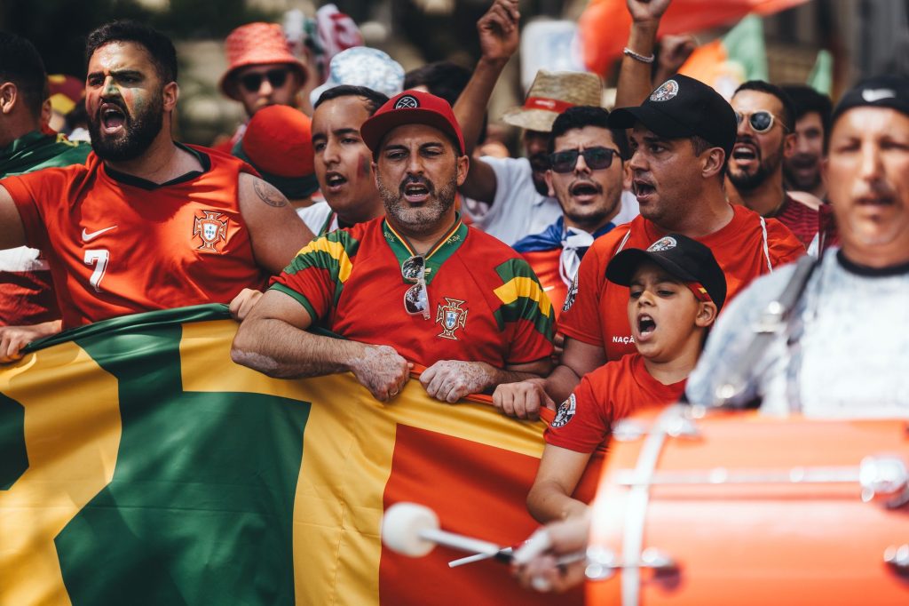 Group of diverse soccer fans cheering passionately, waving flags and celebrating in a vibrant parade.