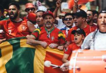 Group of diverse soccer fans cheering passionately, waving flags and celebrating in a vibrant parade.