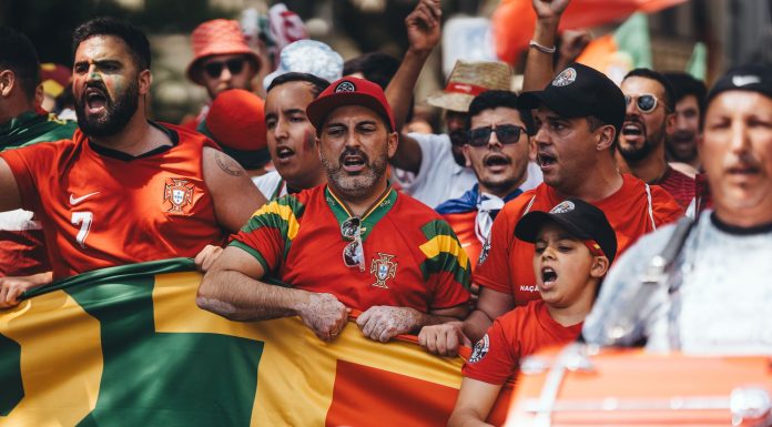 Group of diverse soccer fans cheering passionately, waving flags and celebrating in a vibrant parade.