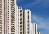 Modern high-rise residential buildings with white facades and blue sky backdrop showcasing urban architecture.