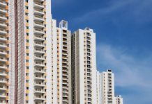 Modern high-rise residential buildings with white facades and blue sky backdrop showcasing urban architecture.