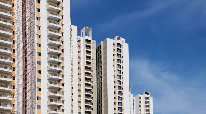 Modern high-rise residential buildings with white facades and blue sky backdrop showcasing urban architecture.
