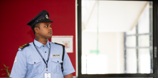 Security guard in uniform standing alert at a building entrance.