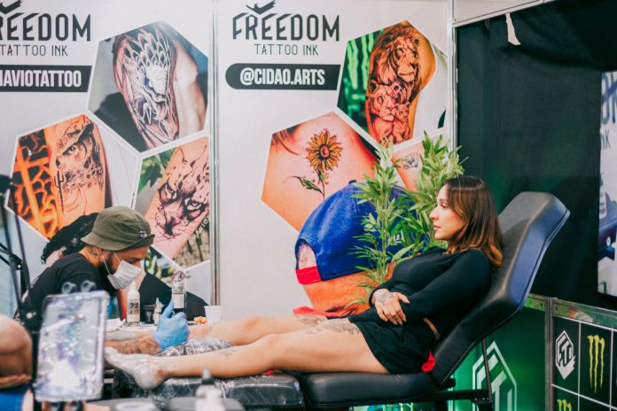 breaking-hudson-county-kicks-off-holiday-weekend-w Tattoo artist creating detailed art in a vibrant studio setting.