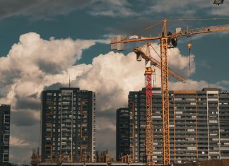 Construction site in Istanbul with cranes and buildings under a dramatic cloudy sky.