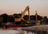 An excavator on a barge near Cove Island Park Marina during twilight in Stamford, Connecticut.