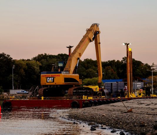 BREAKING: Passaic River Cleanup Moves To In-River Construction An excavator on a barge near Cove Island Park Marina during twilight in Stamford, Connecticut.