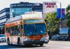Metro bus on Eagle Rock Plaza route in Los Angeles, passing iconic Trader Joe's on a sunny day.