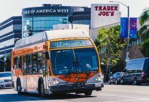 Metro bus on Eagle Rock Plaza route in Los Angeles, passing iconic Trader Joe's on a sunny day.