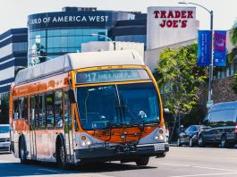 Metro bus on Eagle Rock Plaza route in Los Angeles, passing iconic Trader Joe's on a sunny day.
