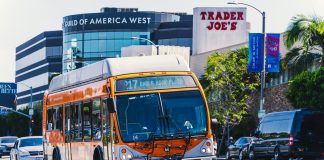 Metro bus on Eagle Rock Plaza route in Los Angeles, passing iconic Trader Joe's on a sunny day.