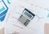 Calculator placed on financial graphs and reports showcasing data analysis and business documentation.