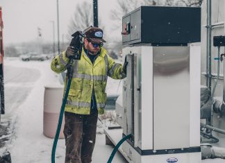 Diesel Spill in Secaucus Creek Raises Questions About Data Centers A man wearing a jacket refuels a truck at a gas station during winter with snow falling.